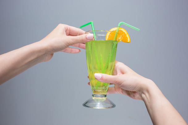 The female hands with cocktail on gray background - Foto, Imagem