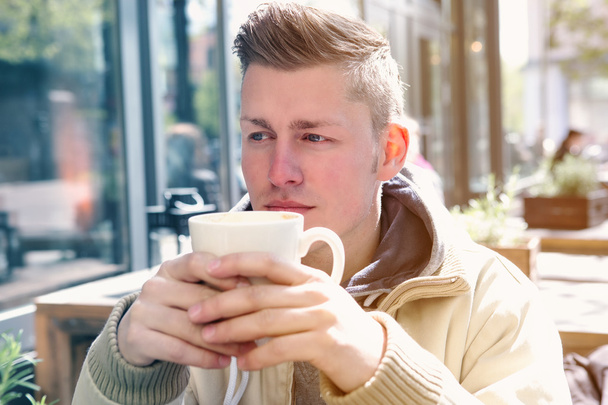 young man sitting outside and drinking coffee - Foto, Imagen