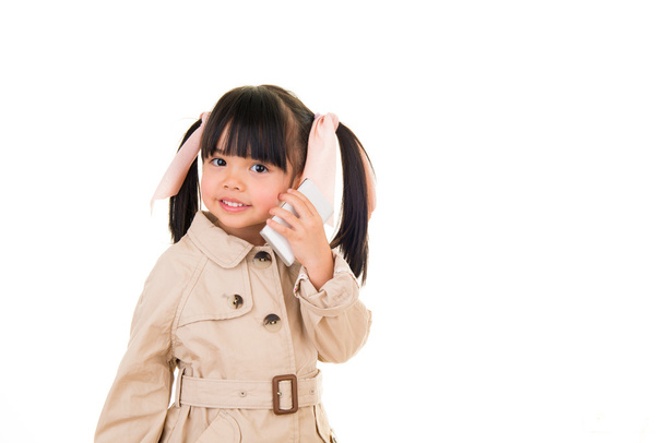 asian smiling little girl talking on the phone isolated on white - Fotó, kép