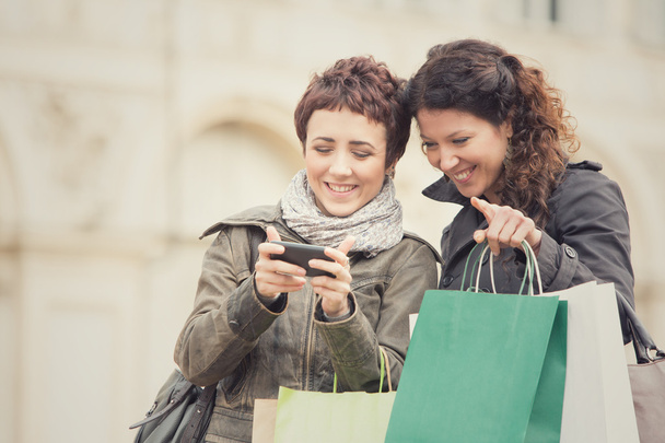 Frauenpaar kauft gemeinsam mit Handy im Stadtbild ein - Foto, Bild