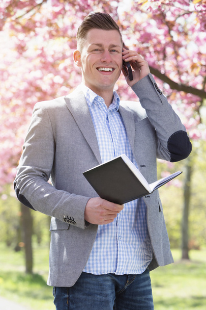 businessman in park with book and phone - Fotoğraf, Görsel