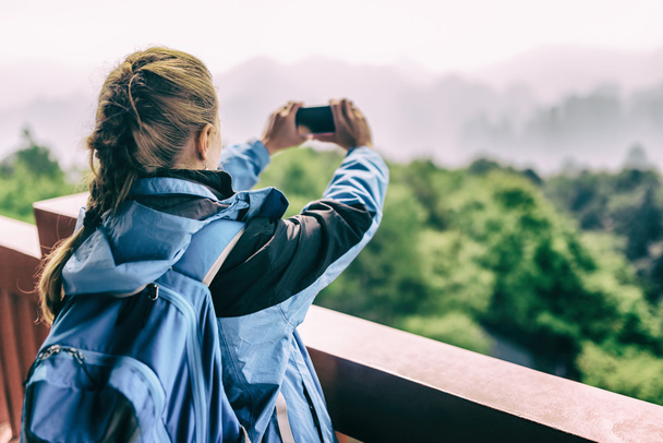 Young female tourist taking photo of mountains. Toned image - Fotografie, Obrázek