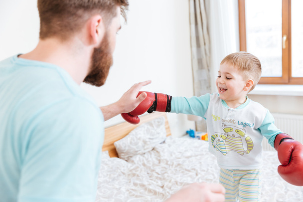 Father playing with his son in boxing gloves at home  - 写真・画像