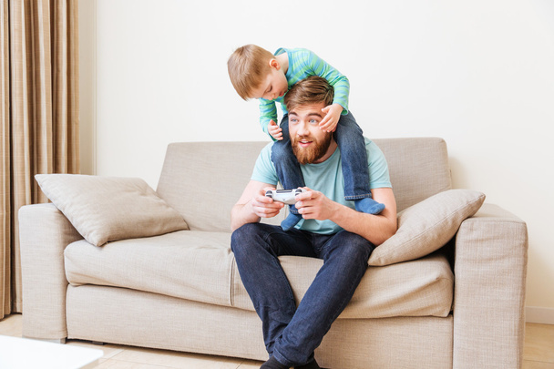Happy man with his son on shoulders playing computer games - Foto, Bild