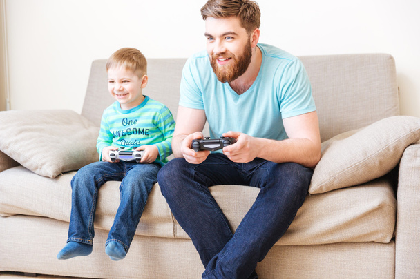 Happy boy playing computer games with his father at home - 写真・画像