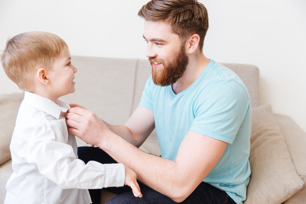 Smiling bearded young father dressing his little son - Foto, immagini