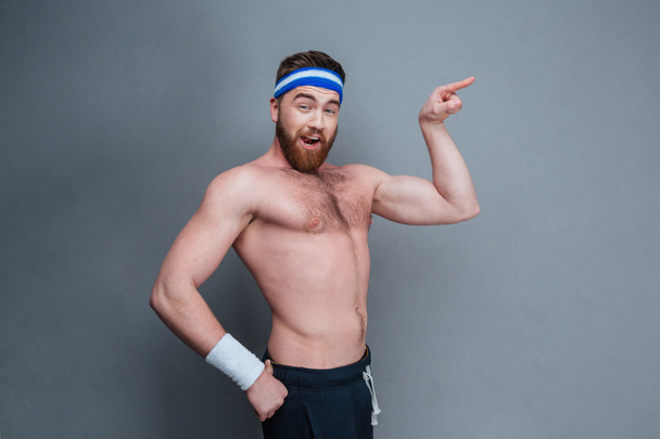 Funny bearded young sportsman pointing away - Foto, Imagen