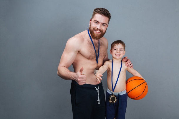 Smiling father and son with golden medals holding basketball ball - Fotoğraf, Görsel