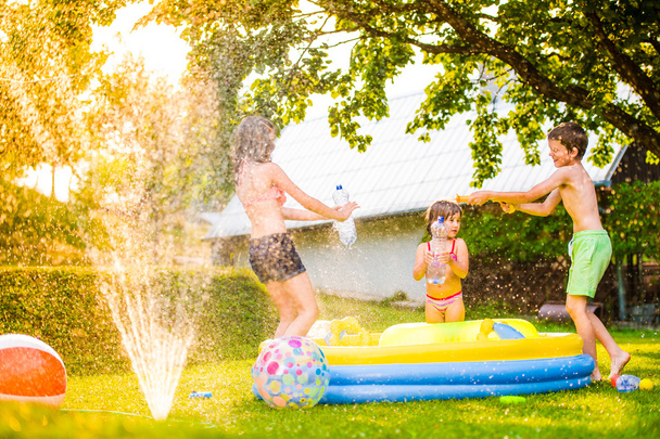 Boy splashing girls with water gun  - Fotoğraf, Görsel