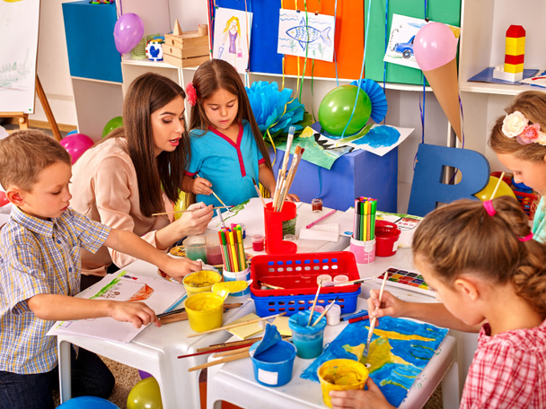 Дети с учительницей рисуют на бумаге в детском саду
 . - Фото, изображение