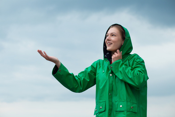 Woman in raincoat at overcast sky background - Foto, imagen