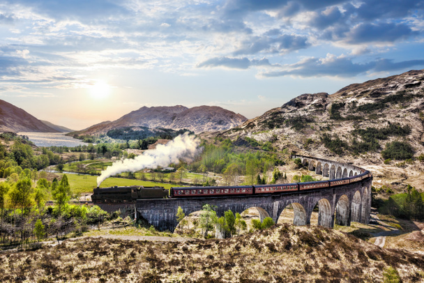 Glenfinnan Railway Viaduct in Scotland with the Jacobite steam train against sunset over lake - Photo, Image