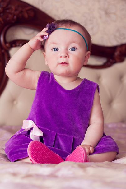 Baby in violet jurk aanraken haar hoofdband - Foto, afbeelding