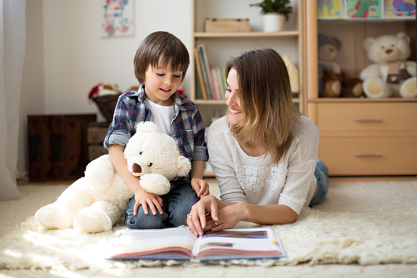 Young mother, read a book to her child, boy in the living room o - Фото, изображение