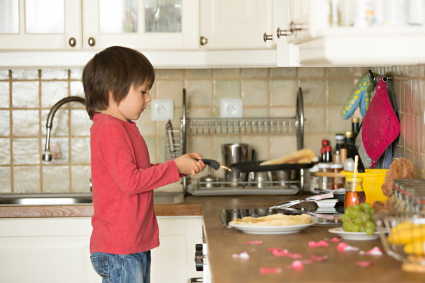 Sweet preschool child, helping his mom in the kitchen, making pa - Photo, image