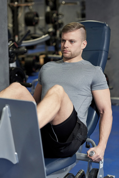 man flexing leg muscles on gym machine - Foto, Bild