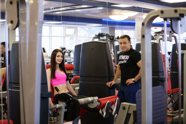 In gym. Fitness trainer and girl posing at camera - Фото, изображение