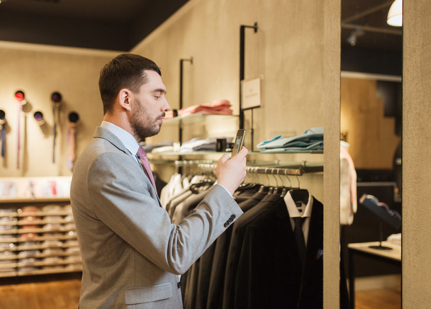man in suit with smartphone at clothing store - Photo, Image