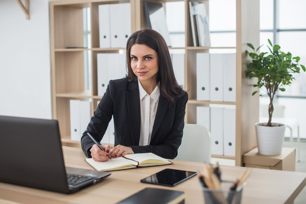 Business woman writes in notebook, office, workplace. - Фото, зображення