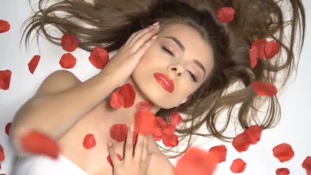 schöne Frau lächelt mit fallenden Rosenblättern - Filmmaterial, Video