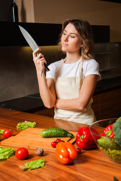 Jolie femme dans la cuisine regardant couteau
 - Photo, image
