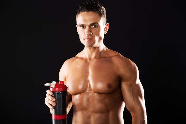 強い運動男は黒の背景に筋肉のついた体を示します。黒の背景に黒 background.muscular のシェーカーと筋肉男性手します。 - 写真・画像