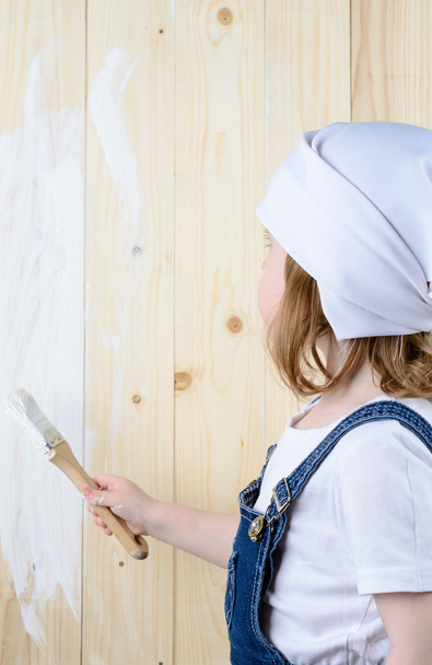 Menina pinta uma parede de madeira
 - Foto, Imagem