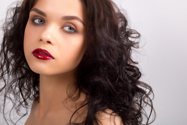 Beauty Model Woman with Long Brown Wavy Hair. Healthy Hair and Beautiful Professional Makeup. Red Lips and Smoky Eyes Make up. Gorgeous Glamour Lady Portrait. Red Manicure. Haircare, Skincare concept - Photo, Image