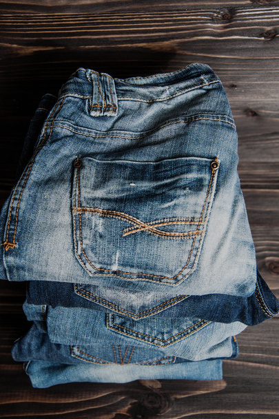 стопка различных оттенков синих джинсов на деревянном фоне
 - Фото, изображение