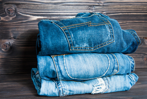 Pile of  jeans clothes on wooden background. - Photo, Image