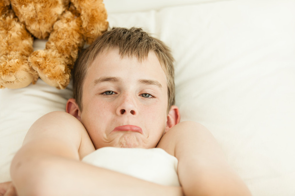 Pouting garçon dans le lit couvert de couverture
 - Photo, image