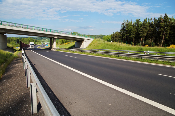 緑豊かな風景の中の高速道路のコンクリート橋の下入る白いトラック - 写真・画像
