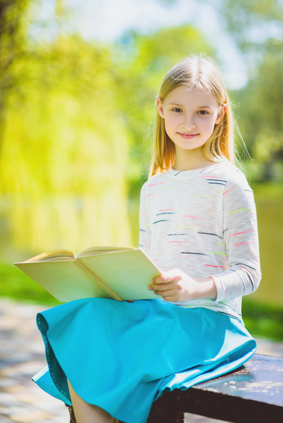 Feliz elegante niña sonriendo celebración libro al aire libre
 - Foto, imagen