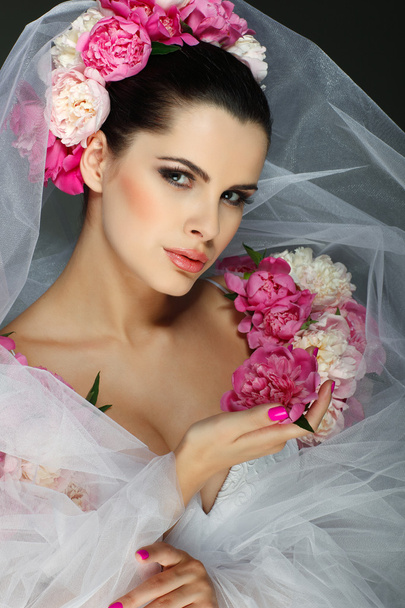 An elegant sexual brunette is in a wedding dress, decorated pink colors - Foto, afbeelding