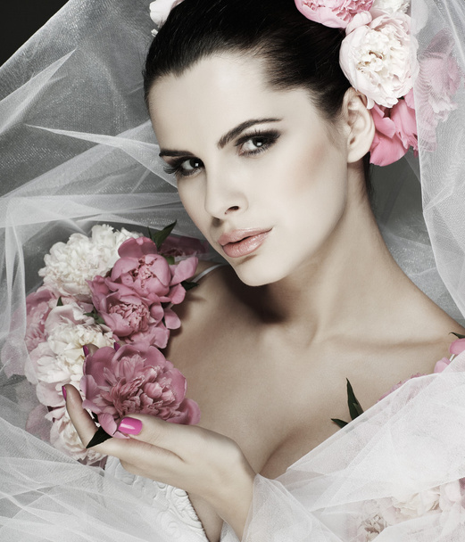 An elegant sexual brunette is in a wedding dress, decorated pink colors - Фото, изображение