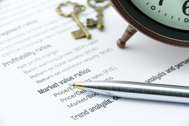 Μπλε στυλό διαρκείας σε λίστες ελέγχου ανάλυσης οικονομικών αναλογιών με ένα ρολόι αντίκα και δύο vintage ορείχαλκο κλειδιά. - Φωτογραφία, εικόνα