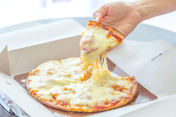Tire de la pizza con la mano
. - Foto, Imagen