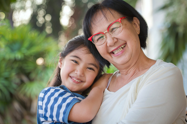 Szczęśliwa dziewczynka azjatyckich przytulanie babci - Zdjęcie, obraz