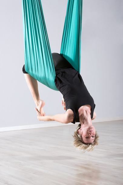 Kopfüber sitzende Frau macht Aerial Yoga - Foto, Bild