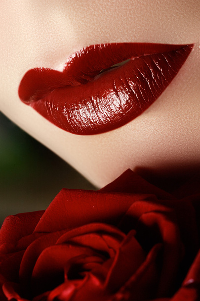 Close-up shot of sexy woman lips with dark red lipstick and beautiful red ros - Photo, Image