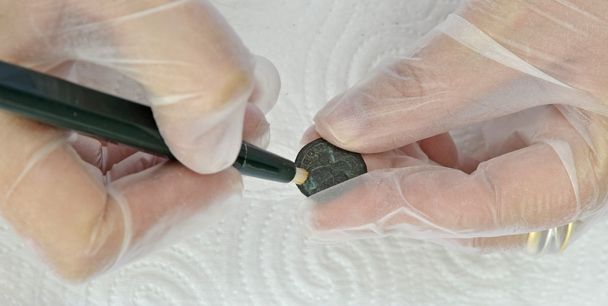 Woman restoring ancient coins with fiberglass - Photo, Image
