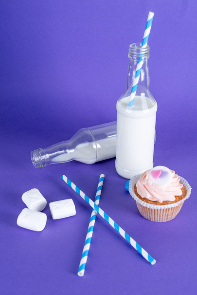 Cócteles de leche con tubos retro, servidos en botellas sobre fondo colorido
. - Foto, Imagen