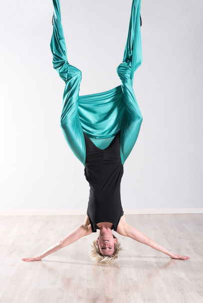 Woman doing aerial yoga upside down on head - 写真・画像