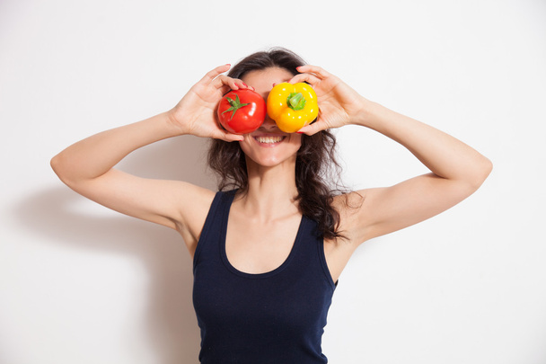 junge Frau bedeckt ihre Augen mit zwei Paprika - Foto, Bild