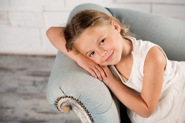 mała dziewczynka siedzi na krześle i uśmiecha się  - Zdjęcie, obraz