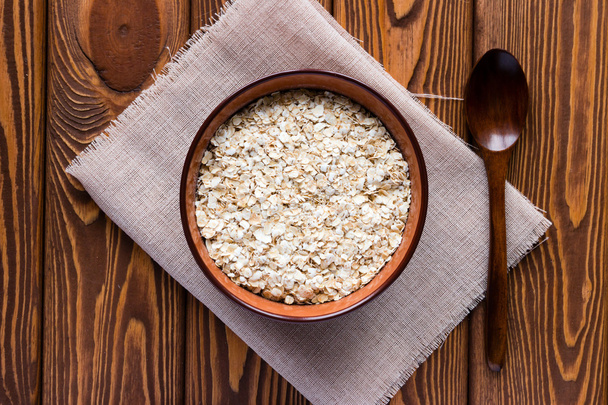 oat flakes in a bowl on a napkin and a wooden spoon - Fotografie, Obrázek