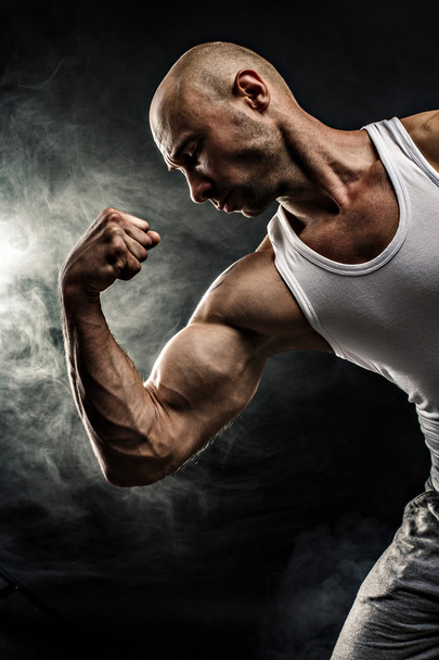 male in white tank top with strong muscles on the black background - Foto, immagini