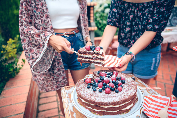 Nő egy nyári partin szolgálatot teljesítő csokoládé torta - Fotó, kép
