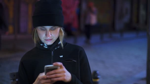 jovem mulher usando um smartphone na rua da noite câmera lenta
 - Filmagem, Vídeo