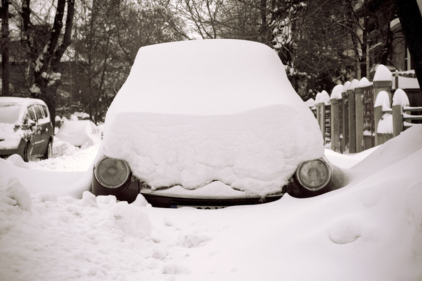 Carro preso na neve em uma rua com apenas faróis mostrando
 - Foto, Imagem